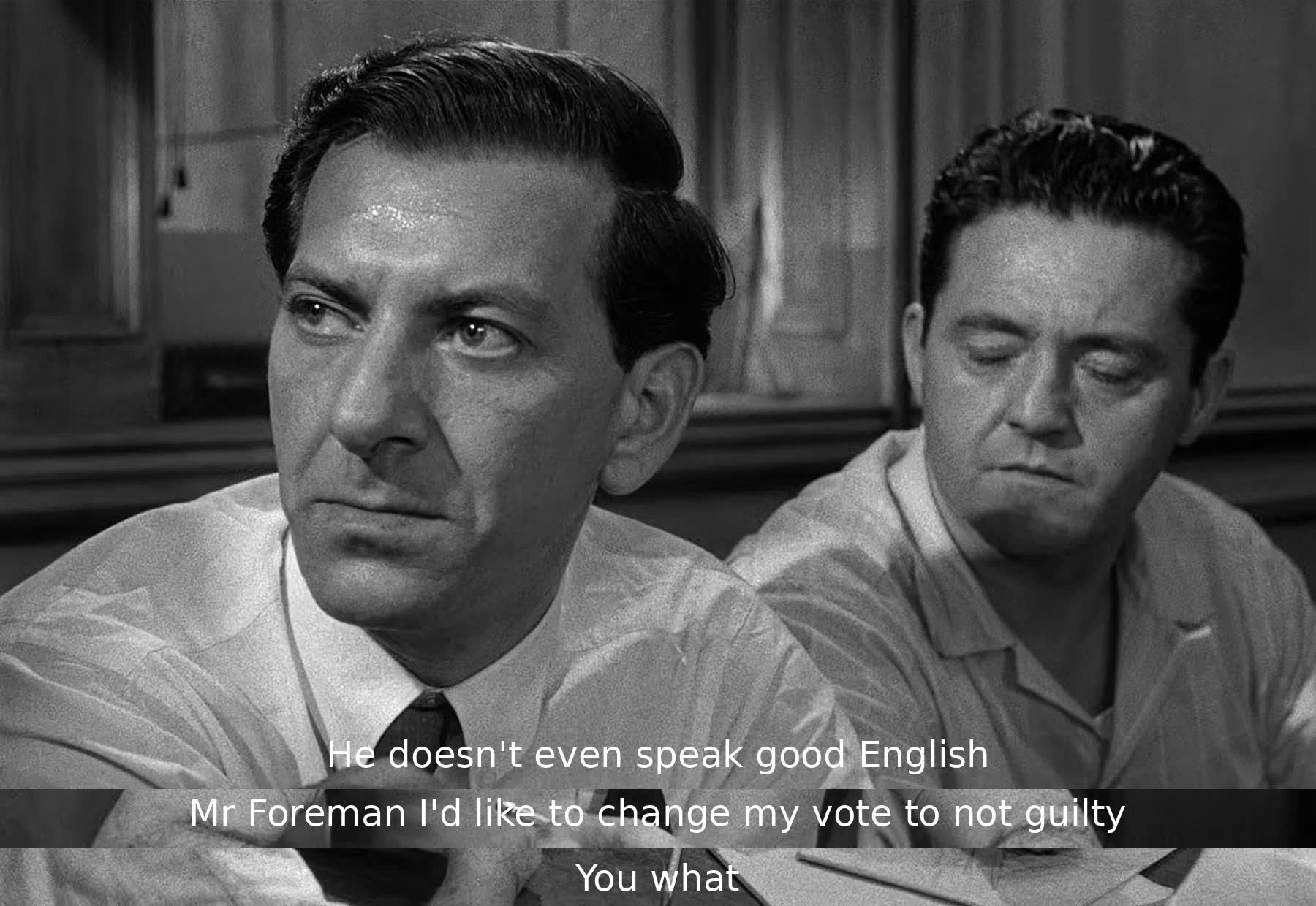 One juror comments on the defendant's English speaking ability. Another juror surprises everyone by changing his vote to not guilty. The foreman is caught off guard by this sudden change.