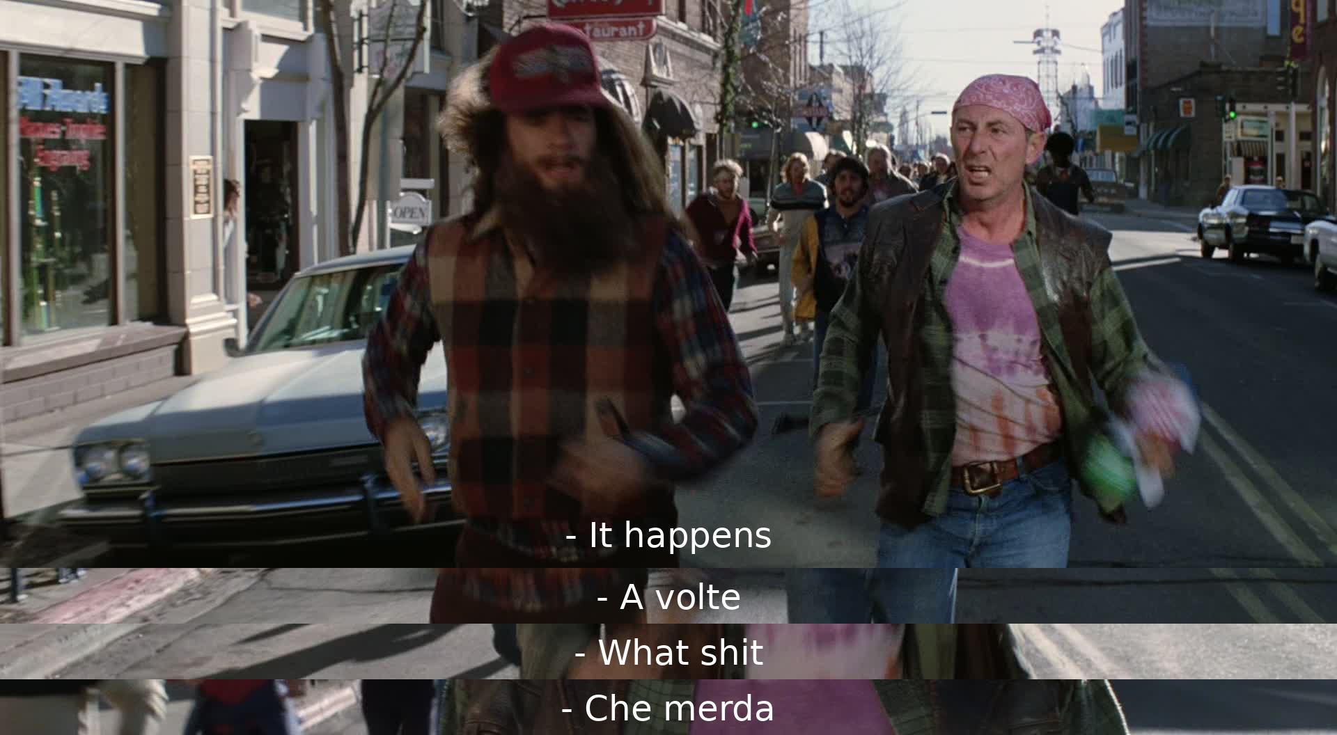 Two characters have a brief exchange in Italian. One says "It happens" (A volte), and the other responds with "What shit" (Che merda).