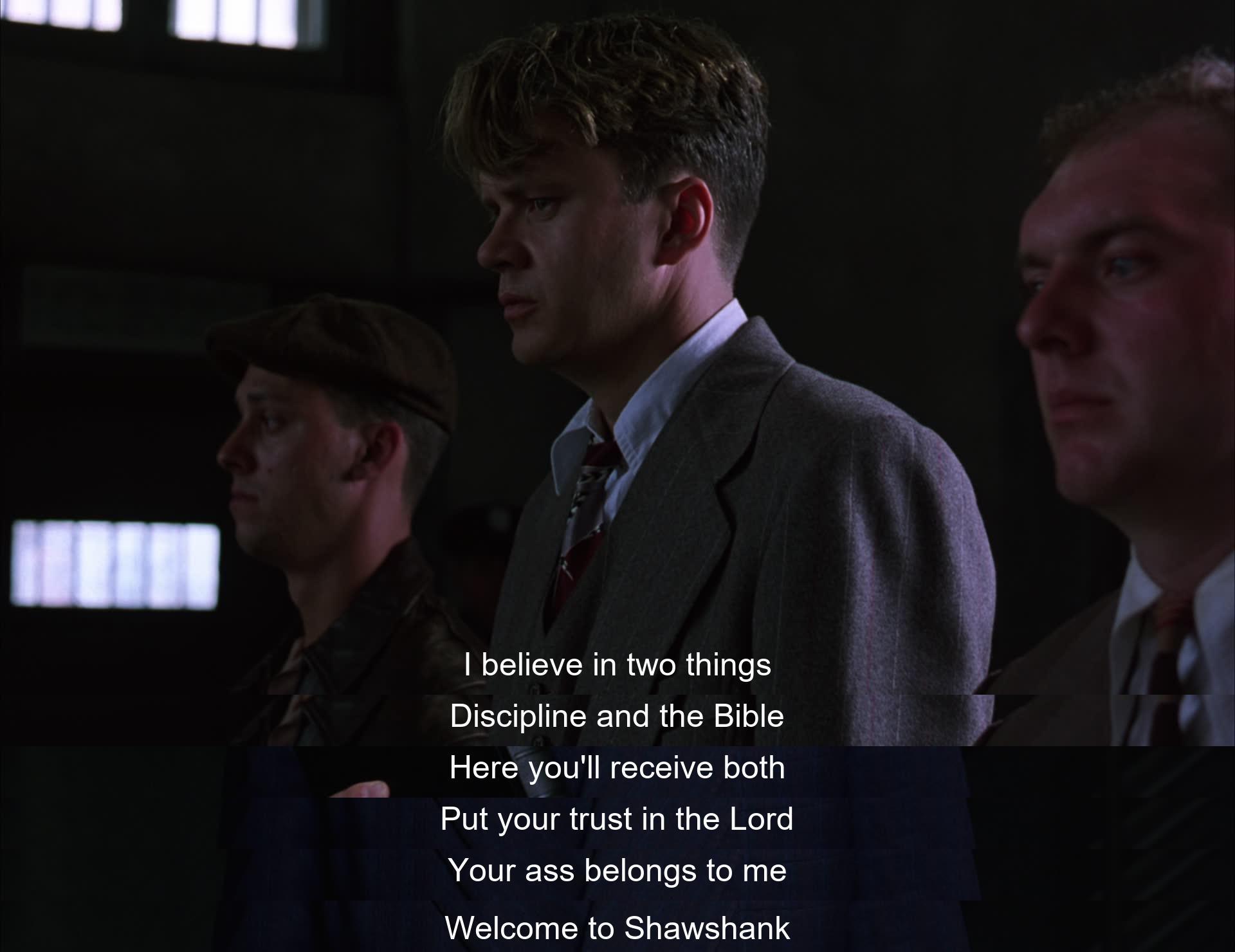 In a stern welcome to Shawshank prison, an authoritative figure emphasizes the importance of discipline and the Bible to the new inmate, asserting control over him by claiming ownership of his well-being with a stern warning and a religious reference.