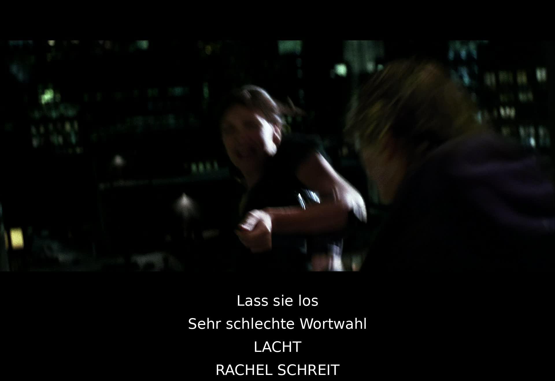 "Erschieß sie" wird verlangt, aber Rachel und Harvey werden gerettet. Rachel ist verängstigt, als Joker flieht. Die Szene enthüllt Jokers grausamen Charakter und Harveys Mut.