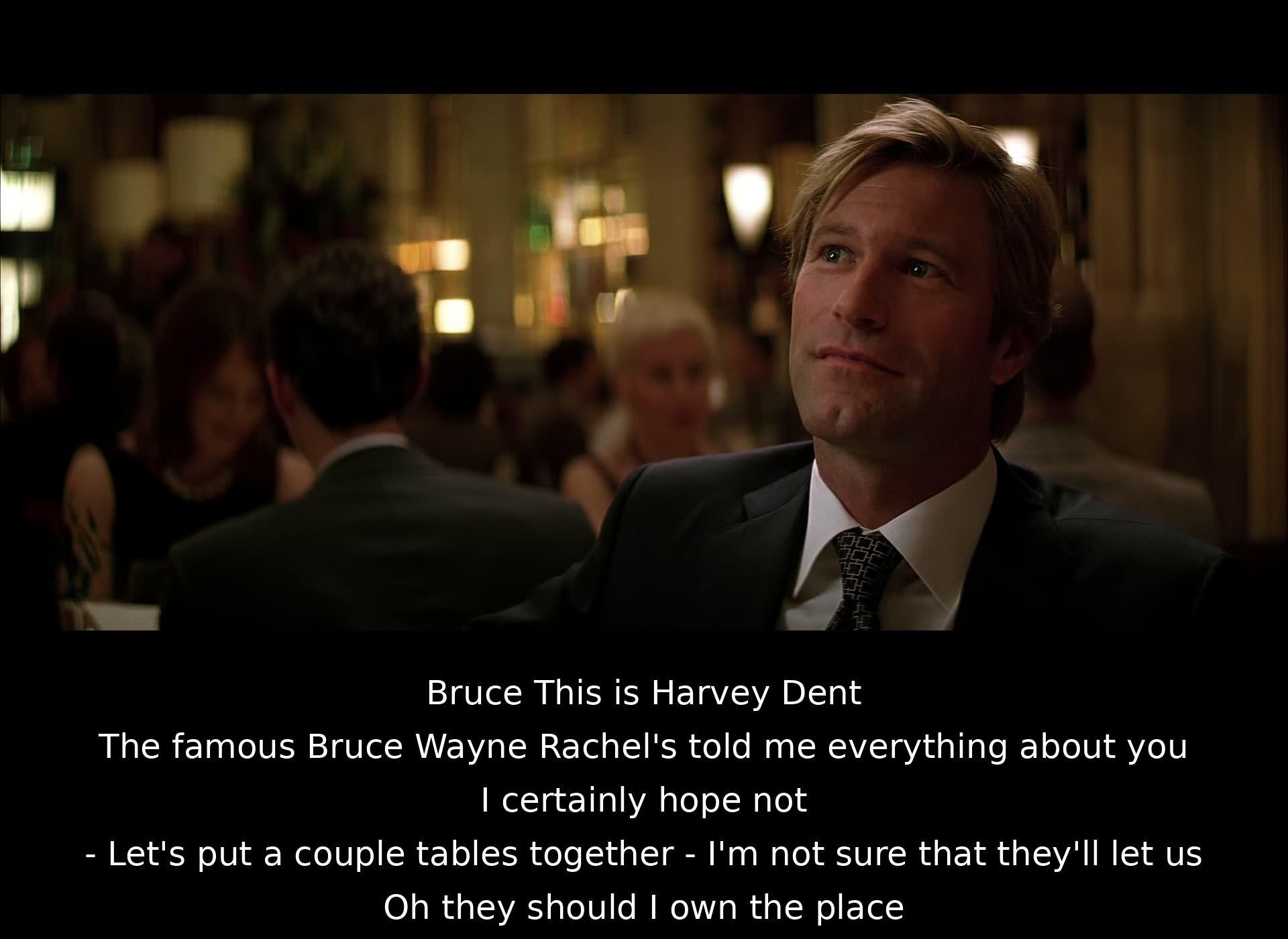 Bruce Wayne introduces Harvey Dent to a group of people, and Dent jokes about Wayne's reputation. Wayne suggests joining tables and Dent mentions Wayne owning the place, implying it won't be a problem.